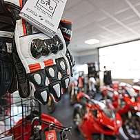 Eine Auswahl an Motorradhandschuhen in einem Verkaufsraum mit Motorrädern.