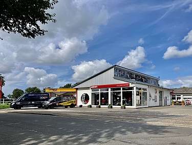 Ein Ducati Motorradgeschäft mit Vans und Wolken am Himmel.