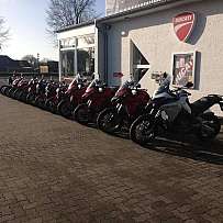 Reihe von Ducati Motorrädern vor einem Verkaufsraum.