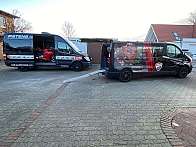 Zwei Transporter mit Motorrädern in einem Hof, einer mit Ducati und der andere mit Aprilia.